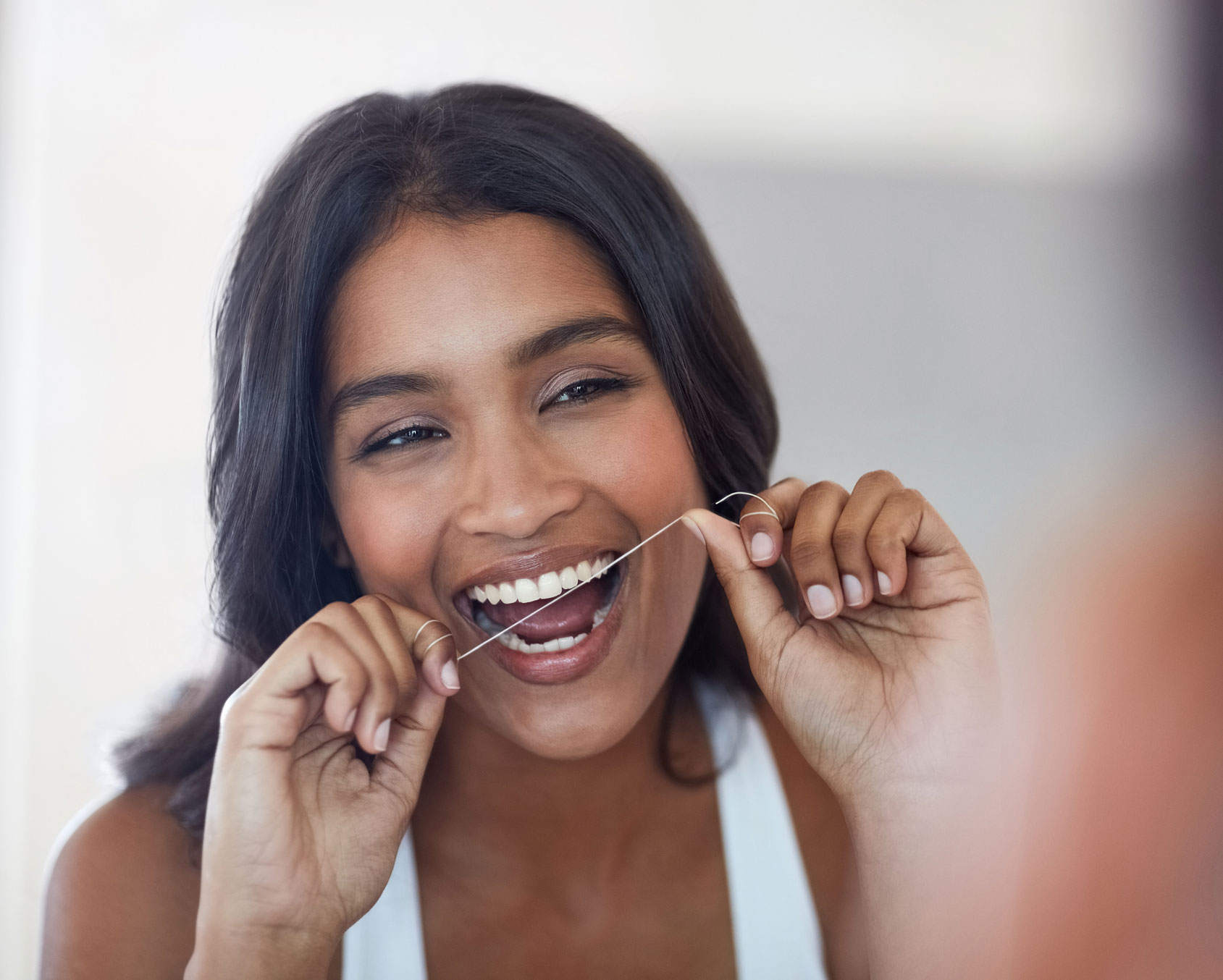 Woman flossing in a mirror